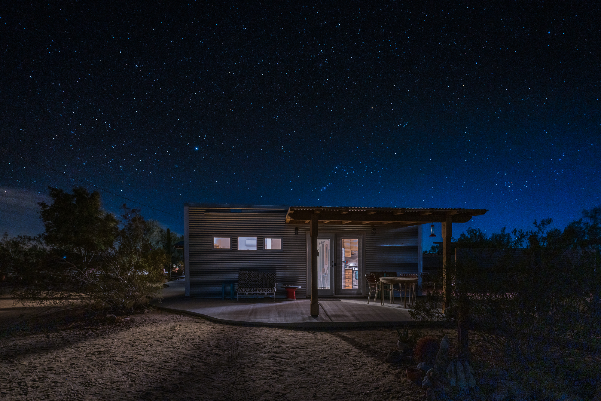 A cozy bungalow nestled in a desert setting at night, with a clear sky showcasing a plethora of stars.