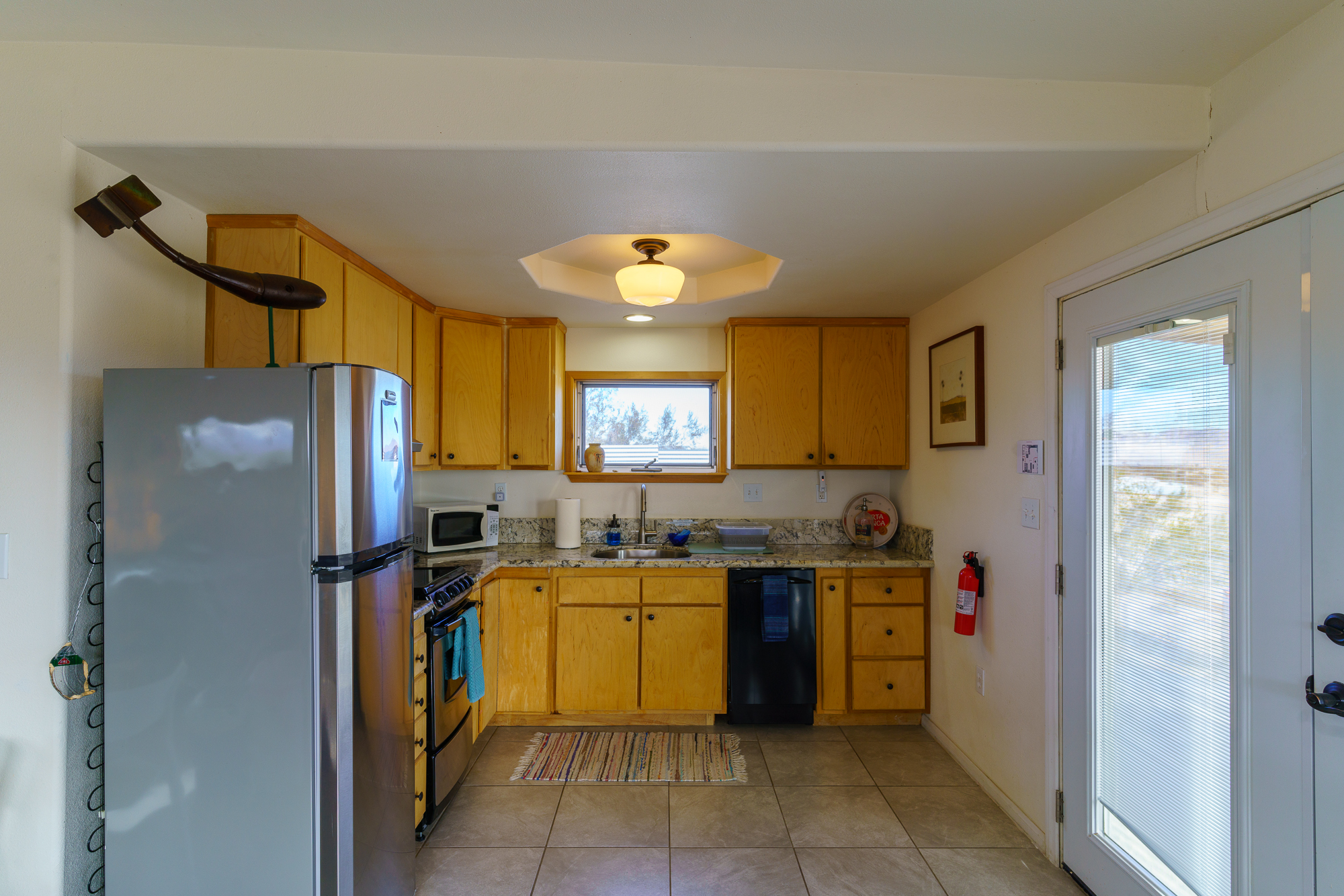 Kitchen of vacation rental with plenty of cabinets and a dishwasher and fire extinguisher to the left.