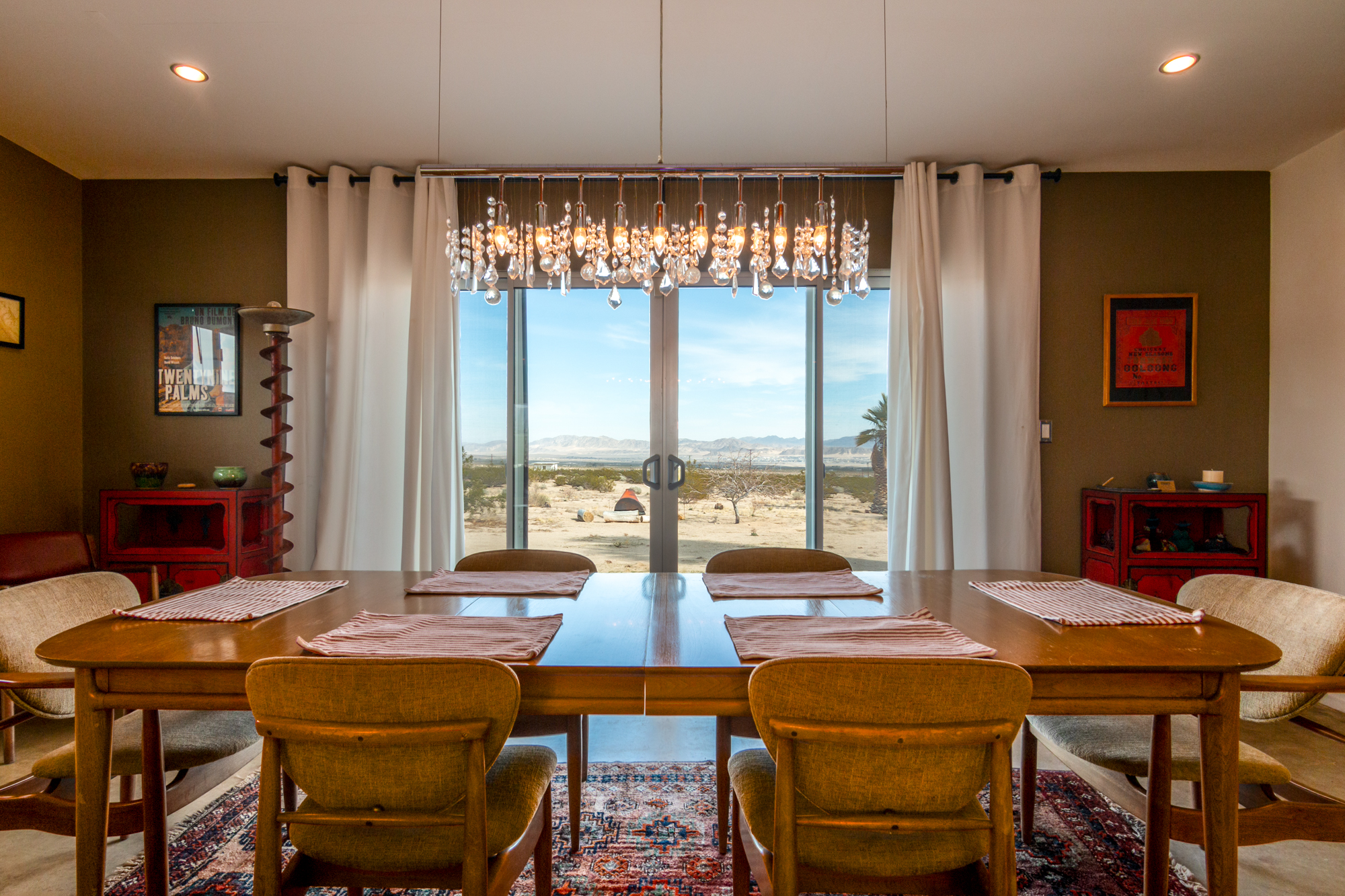 image of a dining room to show the mid-century dining table with the view of the desert outside the french sliding doors