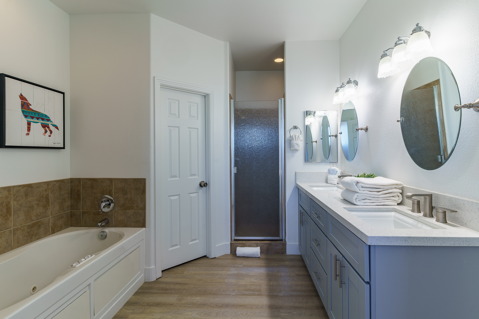 large bathroom with a jetted bathtub, walk-in showers, double sink vanity and two walk-in closets
